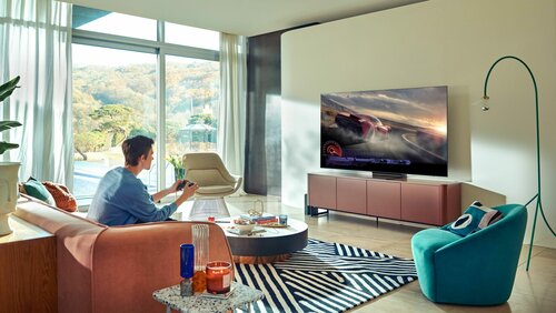 Telewizor LCD Mini LED i grający mężczyzna siedzący na kanapie